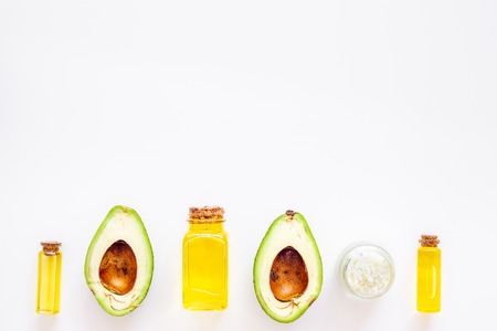 Cosmetics for skin care. Avocado oil near half of an avocado on white backgroundの写真素材