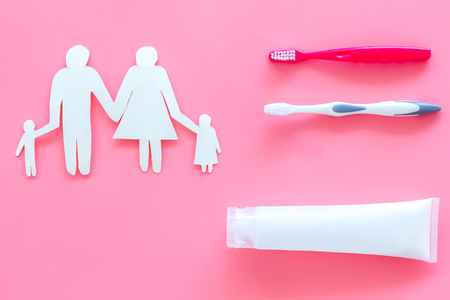 Teeth care, dental care. Set of toothbrushes and tooth paste near family silhouette on pink background top view copy spaceの写真素材