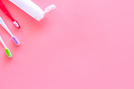 Teeth care, dental care. Toothbrushes and tooth paste on pink background top view.