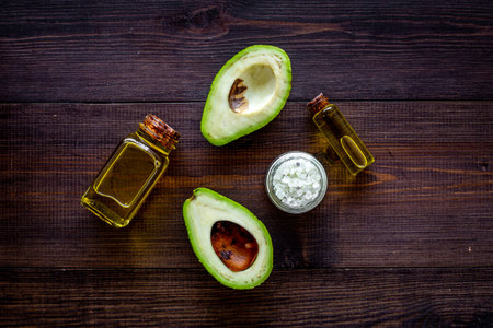 Organic cosmetics with natural ingredients. Avocado essential oil near half of avocado on dark...