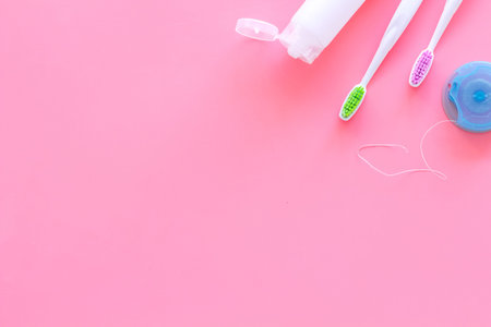 Set for daily teeth care. Toothbrush, tooth paste, dental floss on pink background top view.
