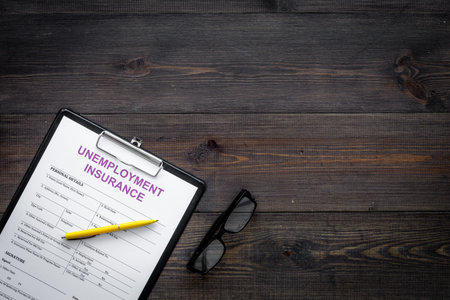 Unemployment insurance form on dark wooden background top view.