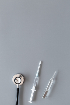 Infuenza, flu vaccine in syringe near stethoscope on grey background top view.の写真素材