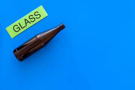 Waste suitable for recycle. Glass bottle near printed word glass on blue background top view.の写真素材