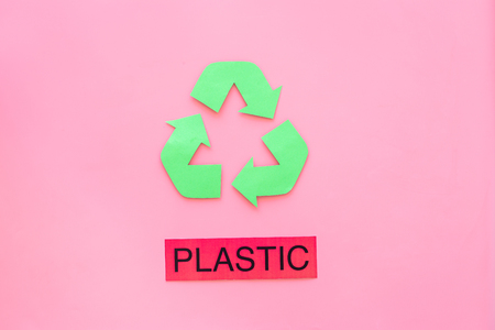 Types of matherial for reycle and reuse. Printed word plastic near eco symbol recycle arrows on pink background top view.の写真素材