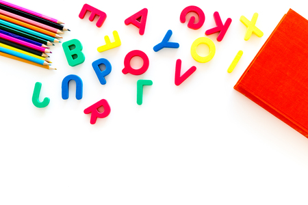 Children learn read concept. Hand hold plastic letters of toy alphabet on white background top view copy spaceの写真素材