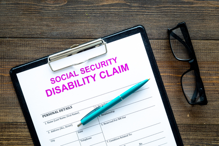Social security. Disability claim form near glasses on dark wooden background top viewの写真素材