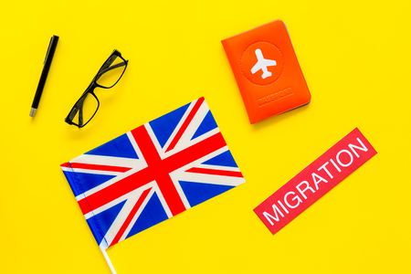 Immigration to Britain concept. Text immigration near passport cover and british flag on yellow background top viewの写真素材