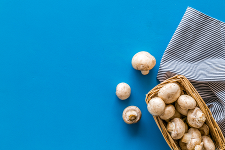 Mushroom champignons. Fresh raw whole champignons in basket on blue background top view copy spaceの写真素材