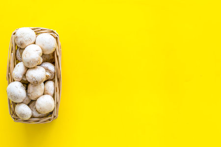 Mushroom champignons. Fresh raw whole champignons in basket on yellow background top view copy spaceの写真素材