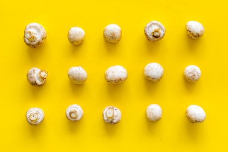 Mushroom champignons pattern. Fresh raw whole champignons on yellow background top viewの写真素材