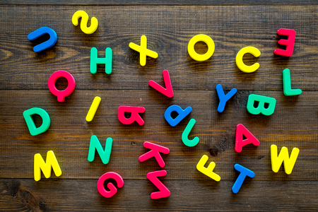 Alphabet for kids concept. English letters in disorder on dark wooden background top viewの写真素材