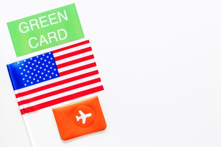 United States of America permanent resident cards. Immigration concept. Text green card near passport cover and US flag top view on white background.の写真素材