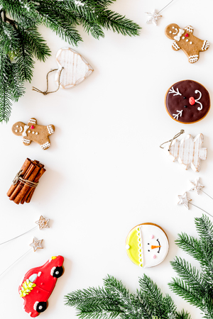 Set of New Year festive ginferbread cookies in shape of gingerbread man, new year spruce, snowman, heart near cinnamon and spruce branch on white background top view copy spaceの写真素材