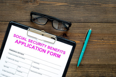 Social security benefits. Application form near pen and glasses on dark wooden background top view...