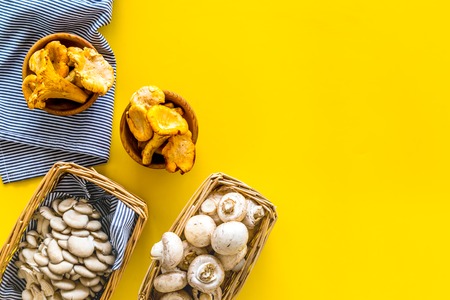 Collect mushroom concept. Champignons, oysters, chanterelles in basket on yellow background top view space for textの写真素材