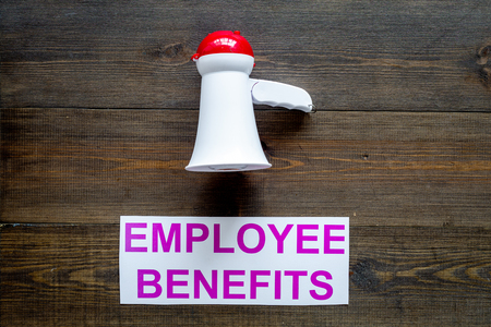 job with social guarantees. Printed words empoyee benefits near megaphone on dark wooden background with computer keyboard top view copy spaceの写真素材