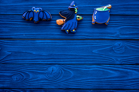 Homemade halloween cookies. Glazed cookies in shape of halloween evils like bat, witch on blue  wooden background top view copy spaceの写真素材