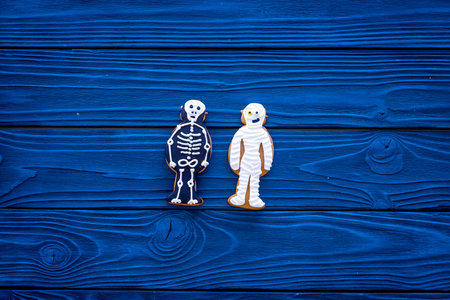Halloween traditions. Halloween gingerbread in shape of evil characters on blue wooden background...