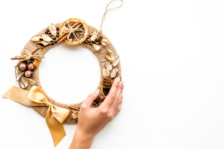 Hand hang a creative christmas wreath made of thread, dry fruits and nuts on white background top view copy spaceの写真素材