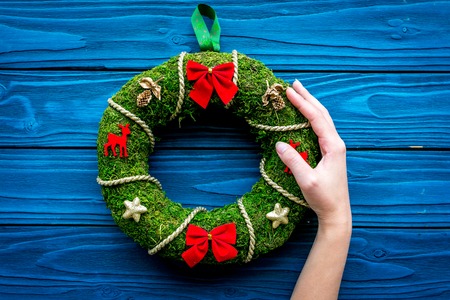 Hand hang a classic christmas wreath on blue wooden background top view copy spaceの写真素材