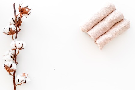 Spa concept. Set of towels twisted coil near cotton flowers on white background top view copy spaceの写真素材