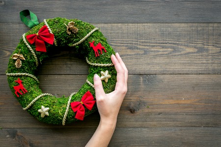 Hand hang a classic christmas wreath on dark wooden background top view.の写真素材