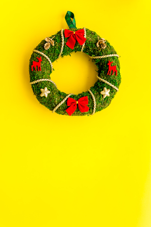 Christmas wreath traditional, classic type. Wreath made of spruce branches and red ribbons on yellow background top view.の写真素材