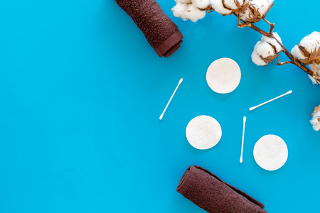 Cotton hygiene products. Cotton pads and swabs, towels twisted coil near dry cotton flowers on blue background top view.の写真素材