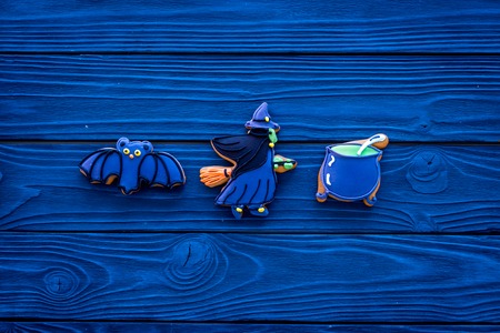 Homemade halloween cookies. Glazed cookies in shape of halloween evils like bat, witch on blue  wooden background top view copy spaceの写真素材