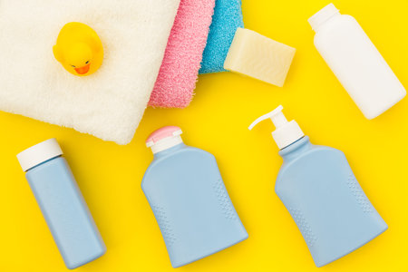 Shower accessories for child. Set with shampoo, towel, soap, gel, towel, brush and yellow rubber duck on yellow background top view patternの写真素材