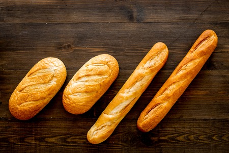 Loaf of white bread and baguette on dark wooden background top view.の写真素材