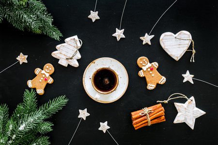 New Year gingerbread cookies. Gingerbread man near coffee, spruce branch, festive decoration on black background top view.の写真素材