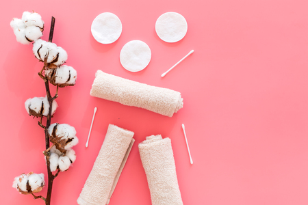 Cotton hygiene products. Cotton pads and swabs, towels twisted coil near dry cotton flowers on pink background top view.の写真素材