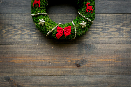 Christmas wreath traditional, classic type. Wreath made of spruce branches and red ribbons on dark wooden background top view.の写真素材