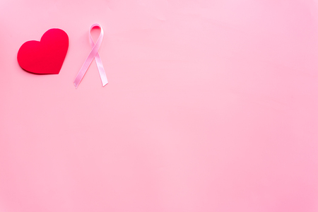 Breast cancer. Mammalogy concept. Symbolic pink ribbon near heart sign on pink background top view.の写真素材