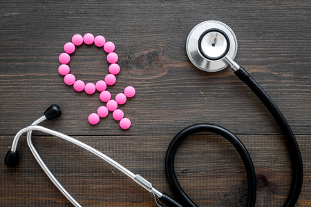 Female diseases concept. Stethoscope near female sign on dark wooden background top view.の写真素材