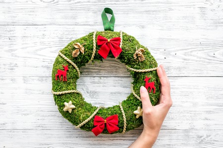 Hand hang a classic christmas wreath on white wooden background top view.の写真素材
