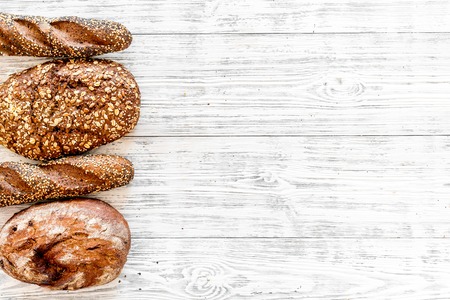 Fitness-bread. Bread made of whole grain flour. Loaf of brown bread and baguette on white wooden background top view copy spaceの写真素材