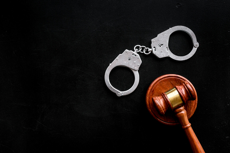 Crime concept. Metal handcuffs near judge gavel on black background top view space for textの写真素材