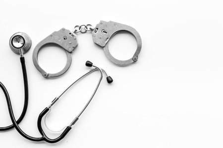 Medical lawsuit. Arrest for medical crime concept. Handcuff near stethoscope on white background top view space for textの写真素材