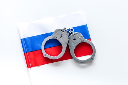 Violation of law, law-breaking concept. Metal handcuffs on russian flag on white background top viewの写真素材