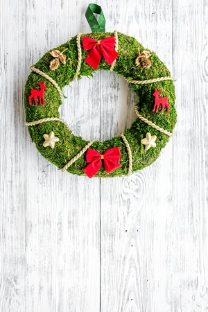 Christmas wreath traditional, classic type. Wreath made of spruce branches and red ribbons on white wooden background top view copy spaceの写真素材