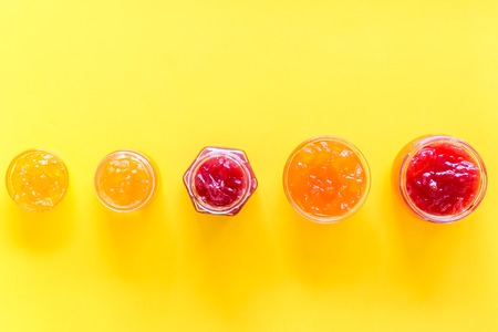 Set of sweet jams in glass jars on yellow background top view copy spaceの写真素材