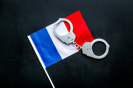 Violation of law, law-breaking concept. Metal handcuffs on French flag on black background top viewの写真素材