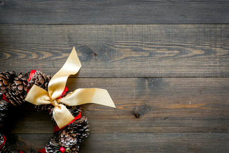 Christmas wreath made of pine cones on dark wooden background top view.