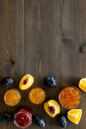 Jams different tastes made of fruits and berries near pieces of fruits on dark wooden background top view copy spaceの写真素材