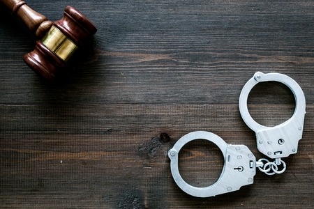 Arrest concept. Metal handcuffs near judge gavel on dark wooden background top view.の写真素材