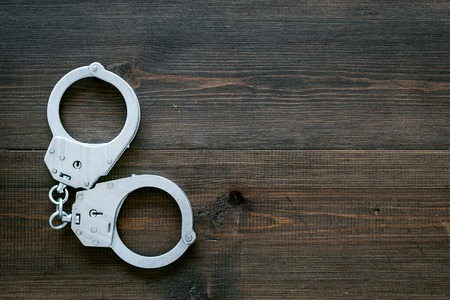 Metal handcuffs on dark wooden background top view.の写真素材