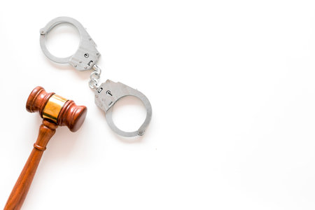 Arrest concept. Metal handcuffs near judge gavel on white background top view.